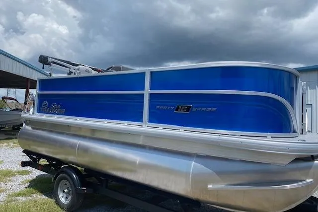 Slide: The Image of 2026 Sun Tracker Party Barge 16 DLX pontoon boat on trailer under cloudy sky. - 5