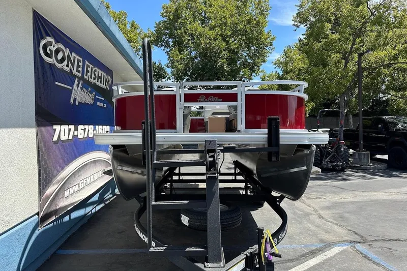 Slide: The Image of 2026 Sun Tracker Bass Buggy 16 XL Select pontoon boat on trailer at dealership. - 2