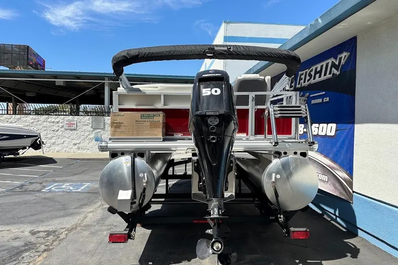 Slide: The Image of 2026 Sun Tracker Bass Buggy 16 XL Select pontoon boat with Mercury 50 engine, parked outdoors. - 7