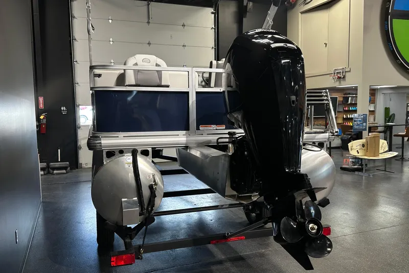 Slide: The Image of 2026 Sun Tracker Bass Buggy 18 DLX pontoon boat with outboard motor in showroom. - 17