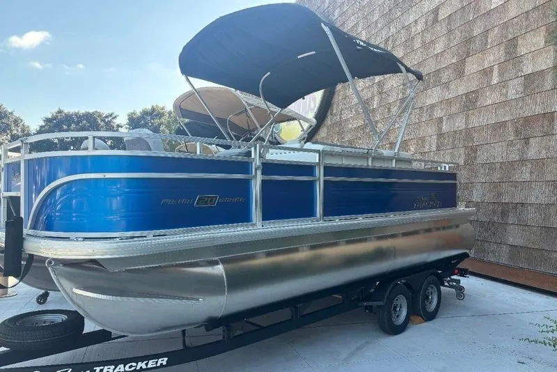 The Image of 2026 Sun Tracker Fishin' Barge 20 DLX pontoon boat on trailer, blue and silver design. - 0