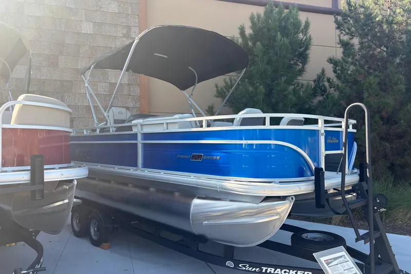 Slide: The Image of 2026 Sun Tracker Fishin' Barge 20 DLX pontoon boat with blue exterior on trailer. - 2