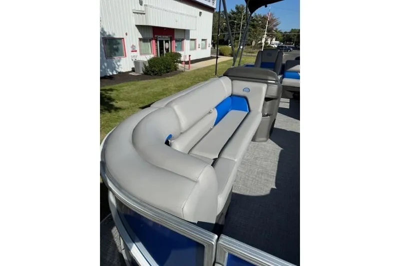 Slide: The Image of 2026 Sun Tracker Party Barge 20 DLX with gray and blue seating, outdoor setting. - 10