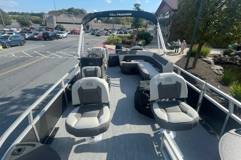 Slide: The Image of 2026 Sun Tracker Bass Buggy 18 DLX pontoon boat parked in a busy lot. - 2