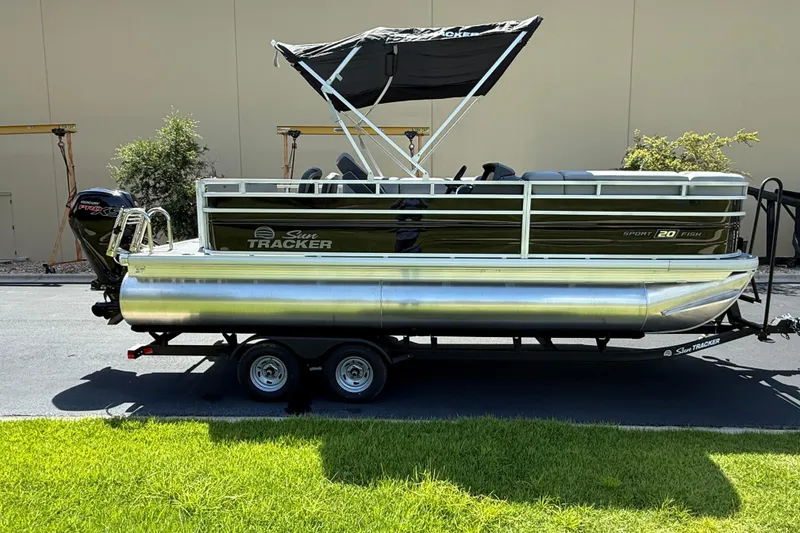 The Image of 2026 Sun Tracker SportFish 20 DLX pontoon boat on trailer, parked outdoors. - 0