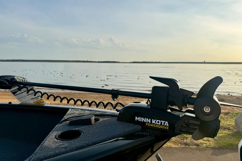 Slide: The Image of 2026 Tracker Super Guide V-16 T boat with Minn Kota PowerDrive motor by a serene lake. - 15