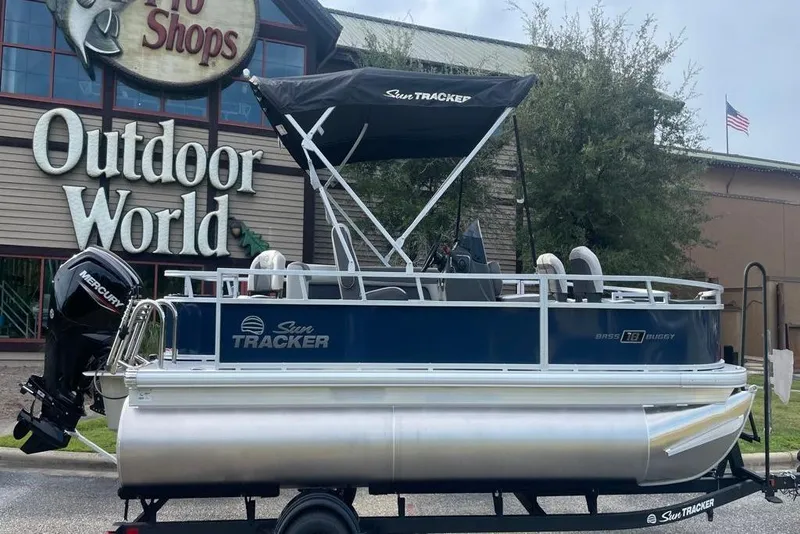 Slide: The Image of 2026 Sun Tracker Bass Buggy 18 DLX pontoon boat outside Outdoor World store. - 3