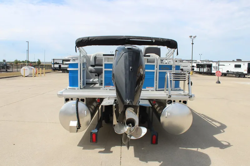 Slide: The Image of 2026 Sun Tracker Fishin' Barge 20 DLX pontoon boat, rear view with motor, parked outdoors. - 6