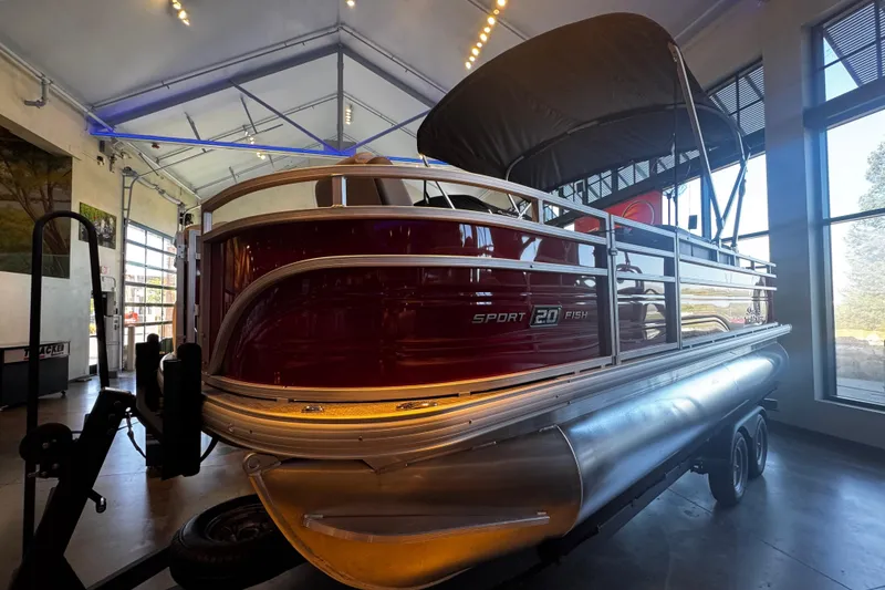 The Image of 2026 Sun Tracker SportFish 20 DLX pontoon boat on trailer, red and silver design. - 0