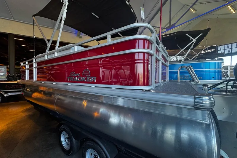 Slide: The Image of 2026 Sun Tracker SportFish 20 DLX pontoon boat with red exterior, parked on a trailer. - 2