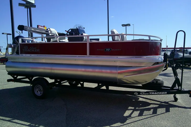 Slide: The Image of 2026 Sun Tracker Bass Buggy 18 DLX pontoon boat on trailer, parked outdoors. - 3