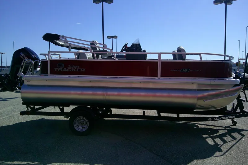 Slide: The Image of 2026 Sun Tracker Bass Buggy 18 DLX pontoon boat on trailer, parked outdoors. - 4