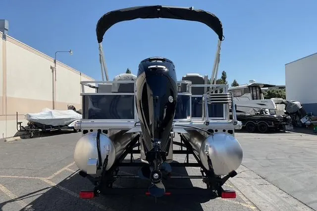 Slide: The Image of 2026 Sun Tracker Bass Buggy 18 DLX pontoon boat, rear view, parked outdoors. - 12