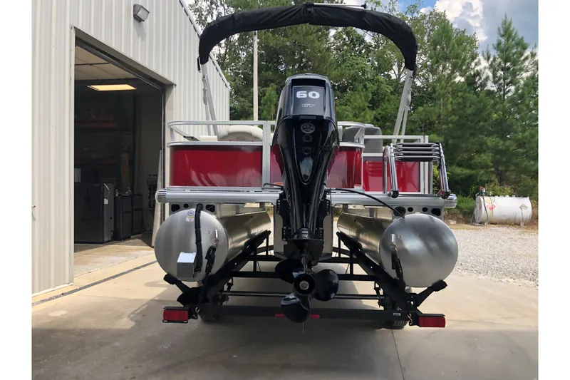 Slide: The Image of 2026 Sun Tracker Bass Buggy 18 DLX pontoon boat with 60 HP engine, parked outdoors. - 20