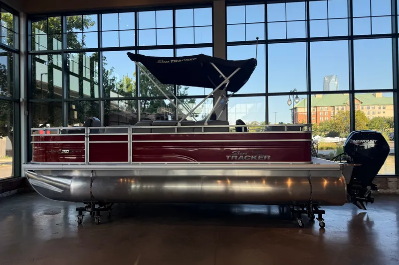 The Image of 2026 Sun Tracker SportFish 20 DLX pontoon boat displayed indoors with scenic window view. - 0