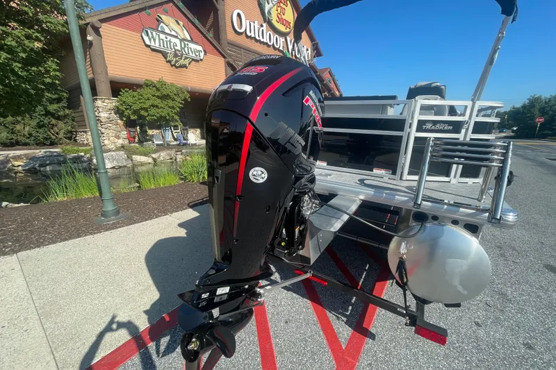 Slide: The Image of 2026 Sun Tracker SportFish 20 DLX pontoon boat with spacious seating in a parking lot. - 2