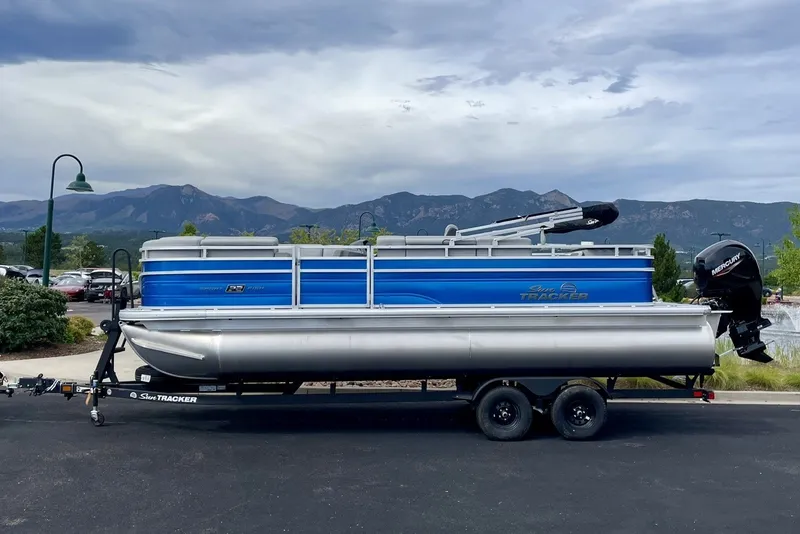 The Image of 2026 Sun Tracker SportFish 20 DLX pontoon boat on trailer, scenic mountain backdrop. - 0