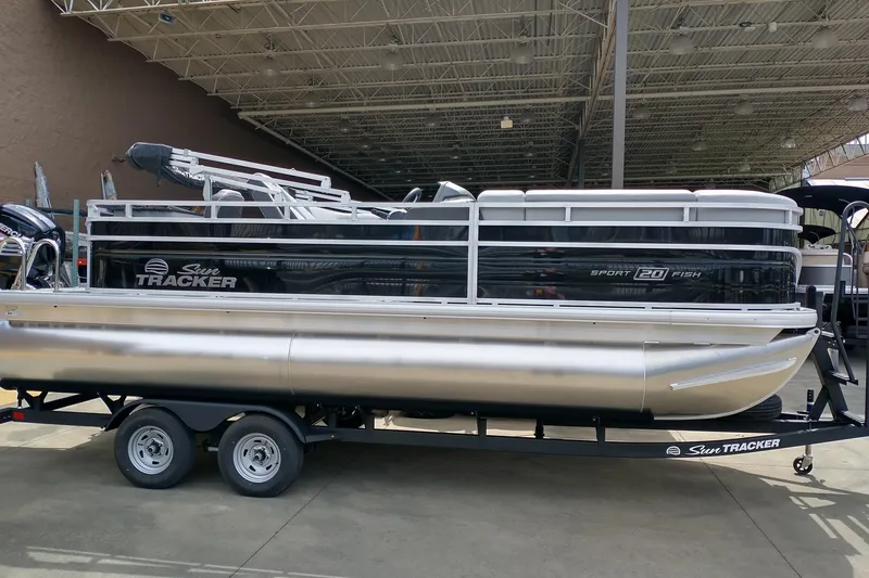 The Image of 2026 Sun Tracker SportFish 20 DLX pontoon boat on a trailer, parked outdoors. - 1