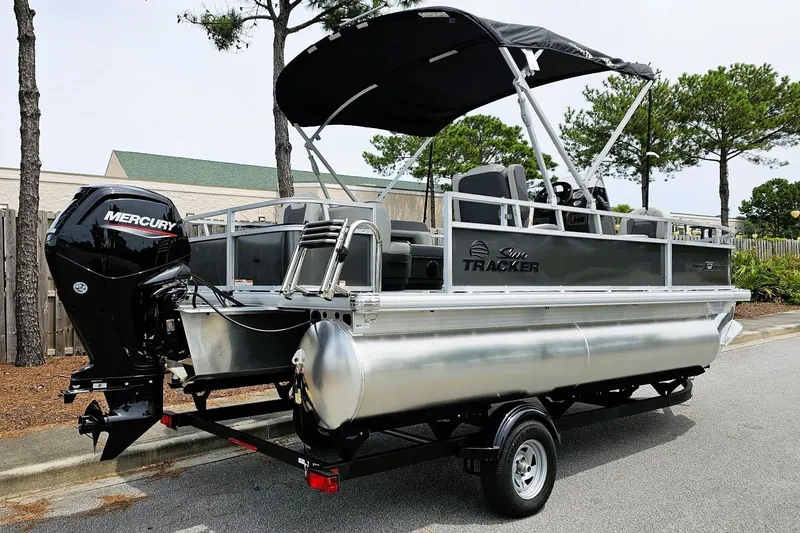 Slide: The Image of 2026 Sun Tracker Bass Buggy 18 DLX pontoon boat with Mercury engine, parked on trailer. - 3