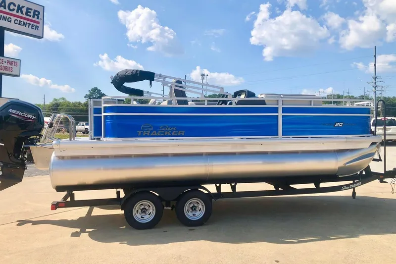 The Image of 2026 Sun Tracker Fishin' Barge 20 DLX pontoon boat on trailer, sunny day. - 0
