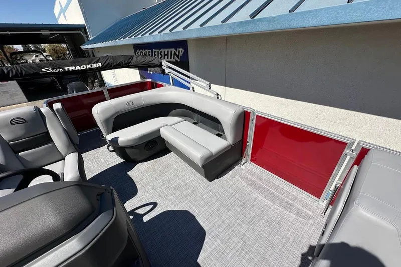 Slide: The Image of 2026 Sun Tracker Party Barge 18 DLX interior with gray seating and red paneling. - 11
