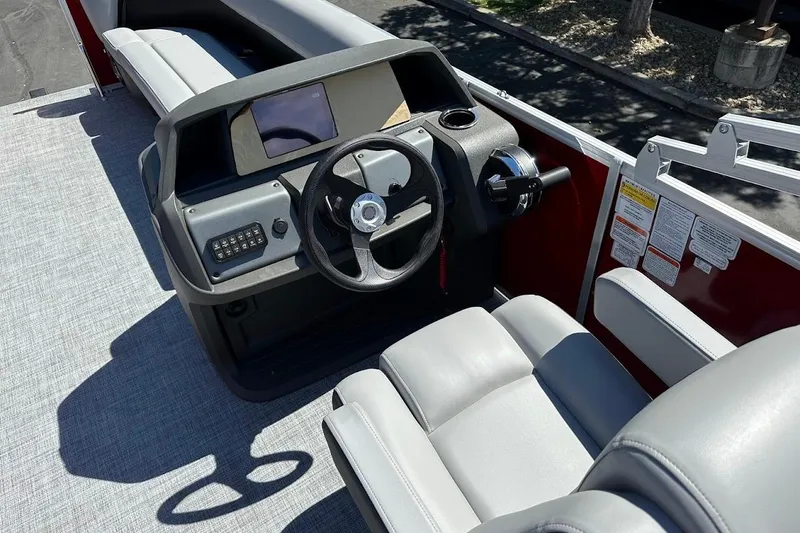 Slide: The Image of 2026 Sun Tracker Party Barge 18 DLX boat interior with steering console and seating. - 18