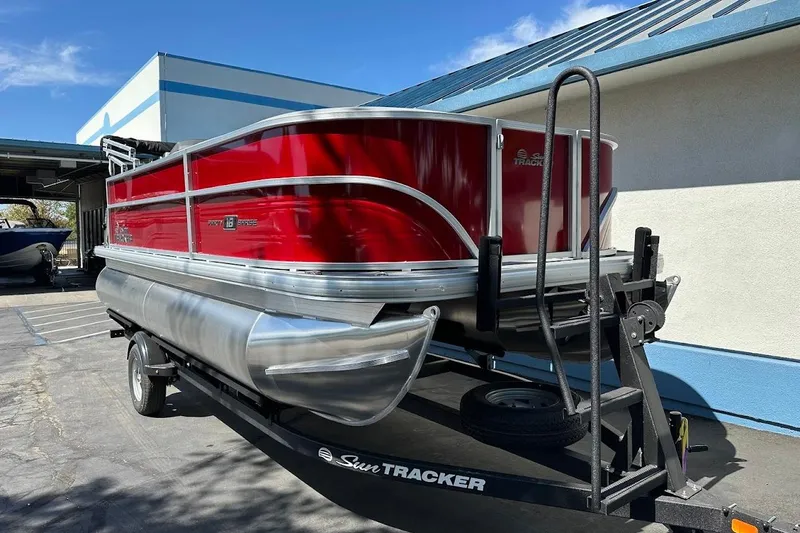 Slide: The Image of 2026 Sun Tracker Party Barge 18 DLX pontoon boat on trailer, vibrant red exterior. - 2