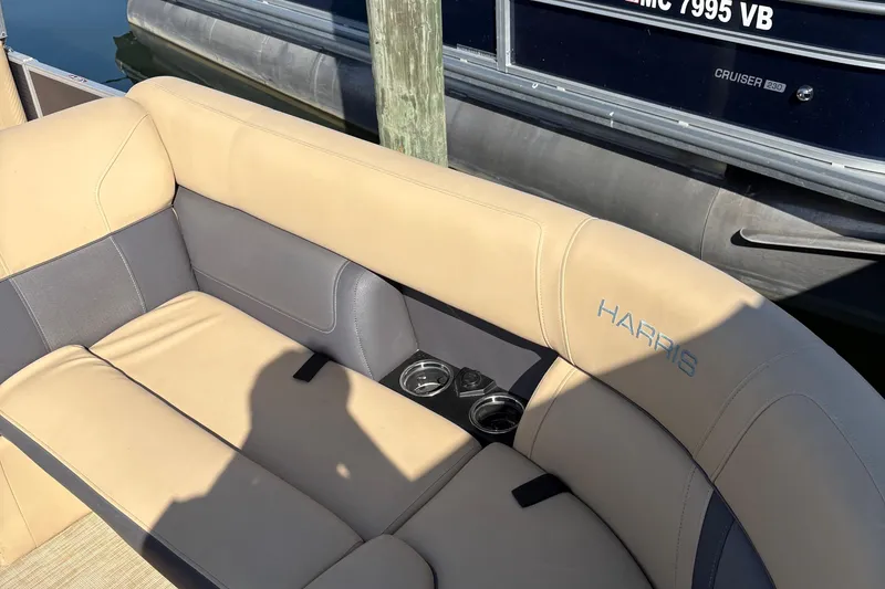 Slide: The Image of 2023 Harris Cruiser boat interior with beige and gray seating, featuring cup holders. - 7