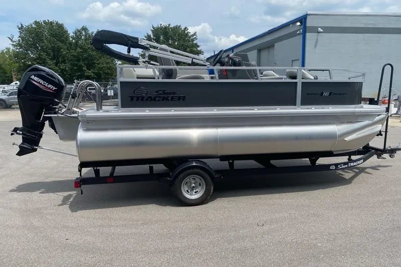 Slide: The Image of 2026 Sun Tracker Bass Buggy 16 XL Select pontoon boat on trailer, parked outdoors. - 78
