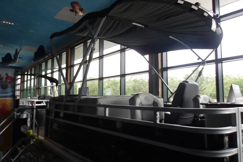 Slide: The Image of 2026 Sun Tracker Fishin' Barge 20 DLX pontoon boat displayed indoors with canopy. - 22