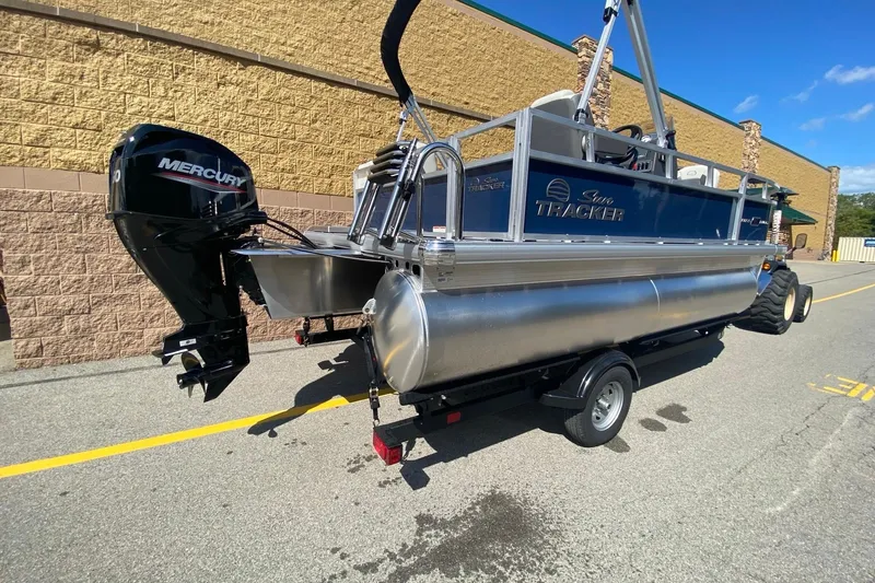 Slide: The Image of 2026 Sun Tracker Bass Buggy 16 XL Select pontoon boat with Mercury engine on trailer. - 2