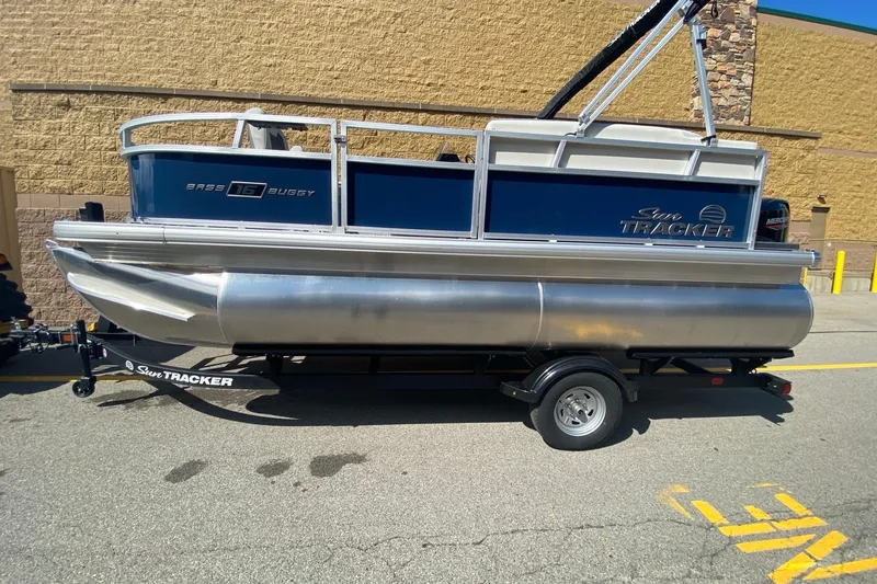 Slide: The Image of 2026 Sun Tracker Bass Buggy 16 XL Select pontoon boat on trailer, parked outdoors. - 3