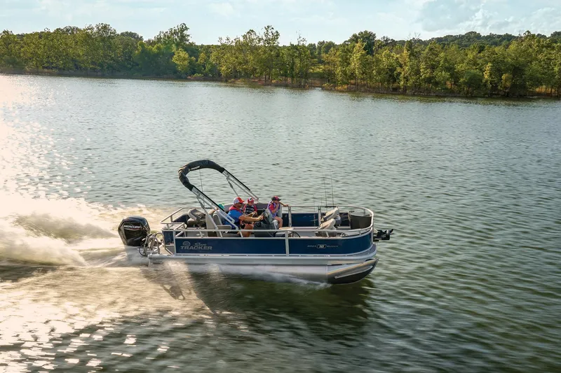Slide: The Image of 2026 Sun Tracker Bass Buggy 18 DLX pontoon boat cruising on a scenic lake. - 20