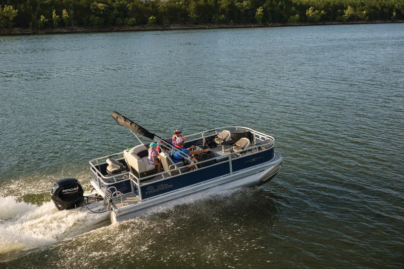 Slide: The Image of 2026 Sun Tracker Bass Buggy 18 DLX pontoon boat cruising on a scenic lake. - 21