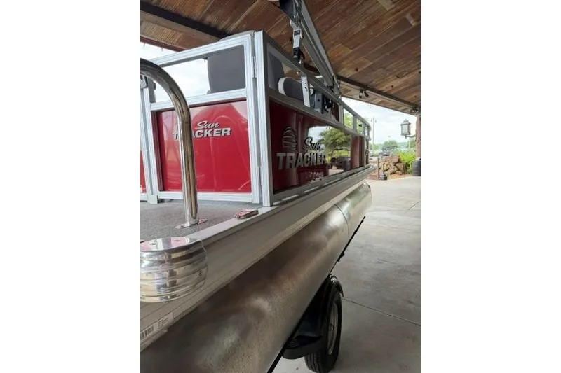 Slide: The Image of 2026 Sun Tracker Bass Buggy 16 XL Select pontoon boat in a covered area. - 2