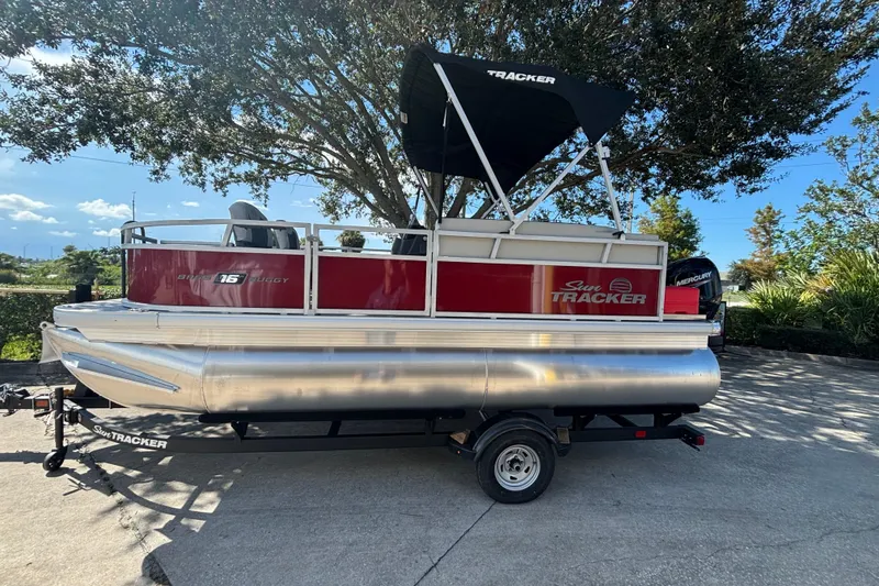 Slide: The Image of 2026 Sun Tracker Bass Buggy 16 XL Select pontoon boat on trailer, parked outdoors. - 76
