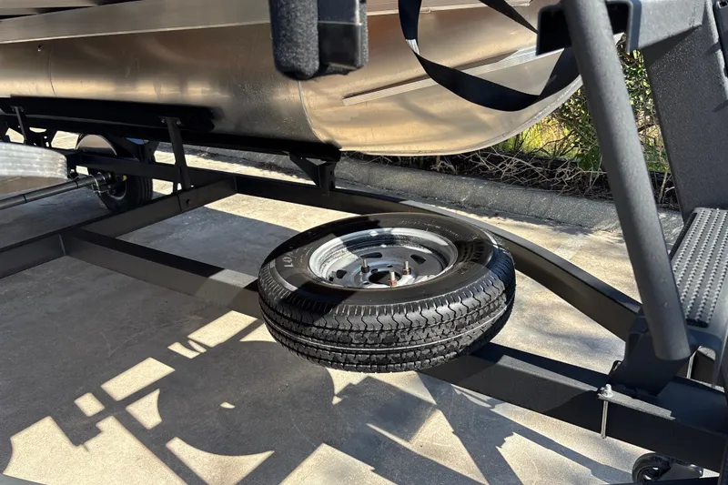 Slide: The Image of 2026 Sun Tracker Bass Buggy 16 XL Select trailer with spare tire in sunlight. - 25