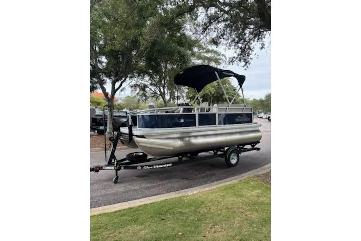 Slide: The Image of 2026 Sun Tracker Bass Buggy 16 XL Select pontoon boat on trailer, parked outdoors. - 4