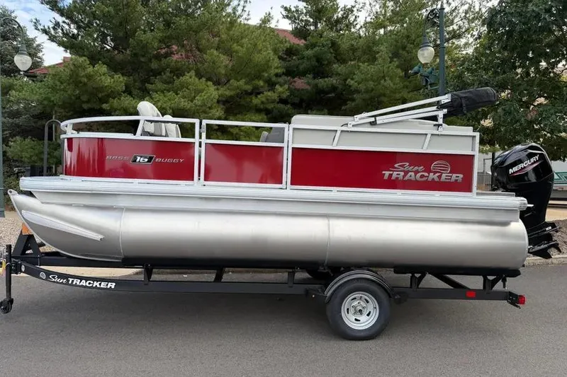 The Image of 2026 Sun Tracker Bass Buggy 16 XL Select pontoon boat on trailer, red and silver design. - 0