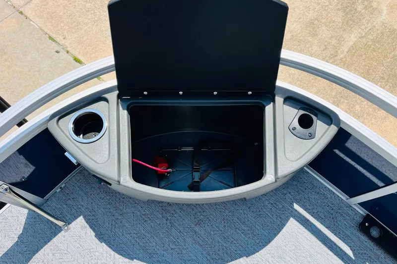 Slide: The Image of 2026 Sun Tracker Bass Buggy 18 DLX storage compartment with cup holders and open lid. - 16