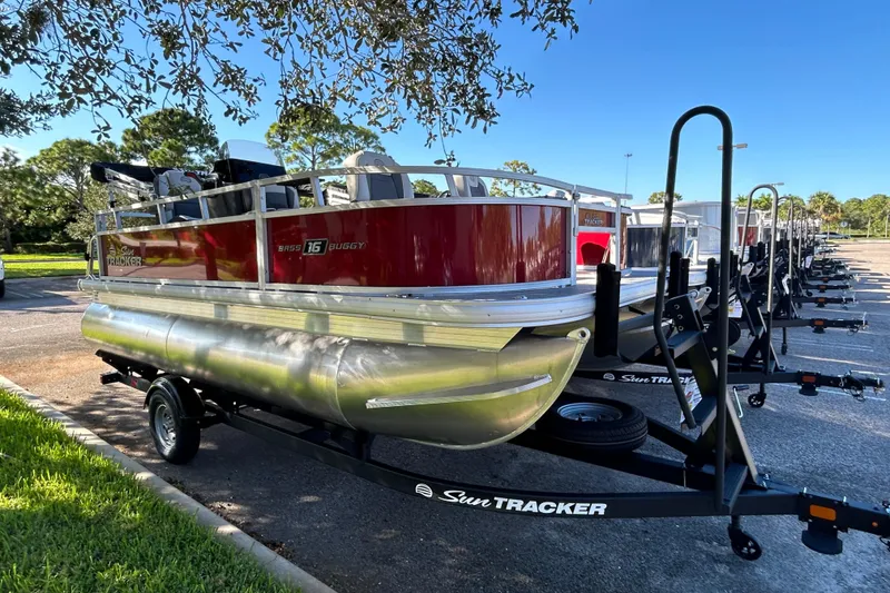 The Image of 2026 Sun Tracker Bass Buggy 16 XL Select pontoon boat on trailer in parking lot. - 0