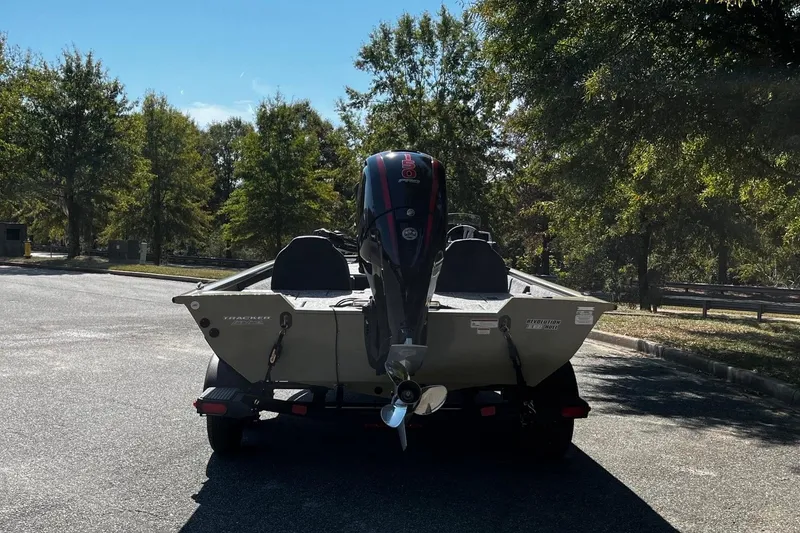 Slide: The Image of 2026 Tracker Pro Team 195 boat on trailer, parked in a sunny, tree-lined area. - 5