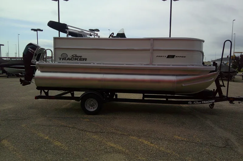 Slide: The Image of 2026 Sun Tracker Party Barge 16 DLX pontoon boat on trailer in parking lot. - 2