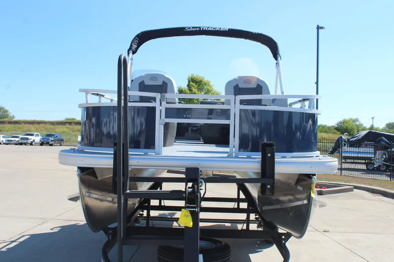 Slide: The Image of 2026 Sun Tracker Bass Buggy 16 XL Select pontoon boat on trailer, outdoor setting. - 2