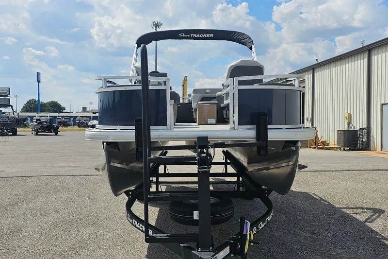 Slide: The Image of 2026 Sun Tracker Bass Buggy 18 DLX pontoon boat on trailer, outdoor dealership setting. - 2
