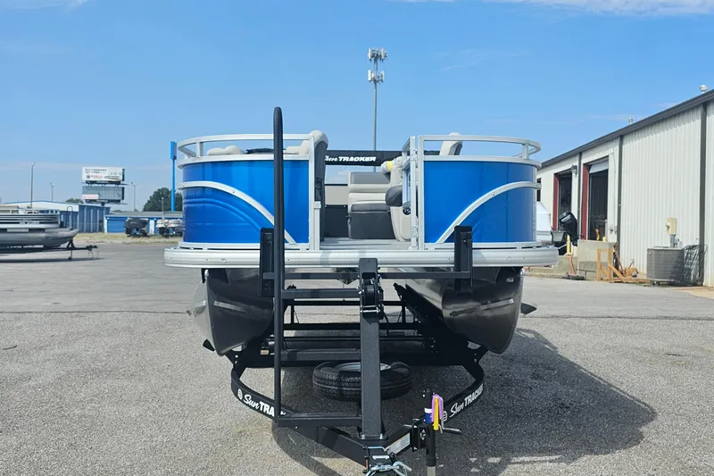 Slide: The Image of 2026 Sun Tracker Fishin' Barge 20 DLX pontoon boat on trailer, outdoor dealership setting. - 2