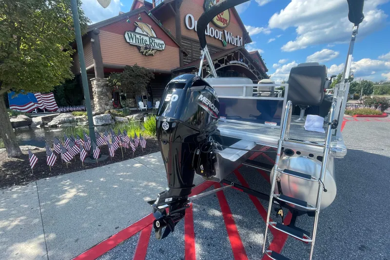 Slide: The Image of 2026 Sun Tracker Bass Buggy 16 XL Select pontoon boat in a parking lot. - 2