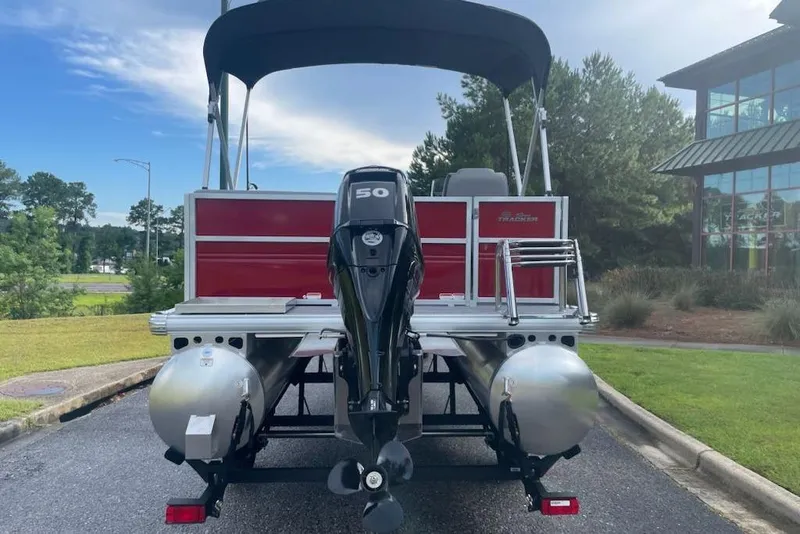 Slide: The Image of 2026 Sun Tracker Party Barge 16 DLX pontoon boat with 50 HP engine, parked outdoors. - 3