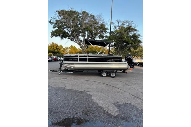 The Image of 2026 Sun Tracker SportFish 20 DLX pontoon boat on trailer in parking lot. - 0