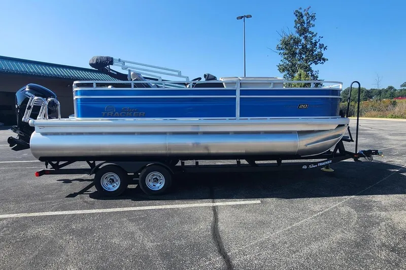 The Image of 2026 Sun Tracker Fishin' Barge 20 DLX pontoon boat on trailer in parking lot. - 0